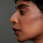 Side profile of woman wearing gold butterfly-shaped nose pin