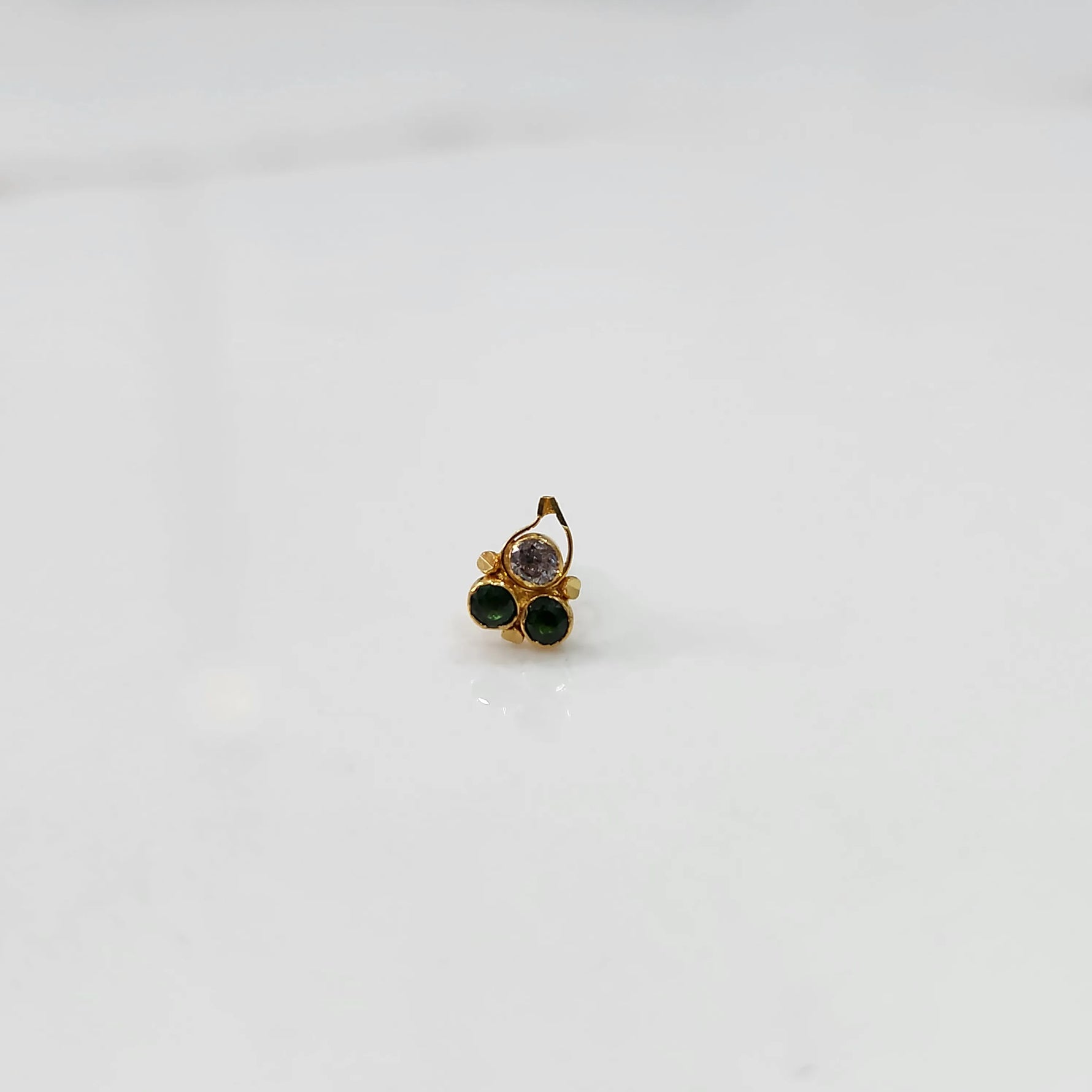 Gold nose pin with clear and green stones, product shot