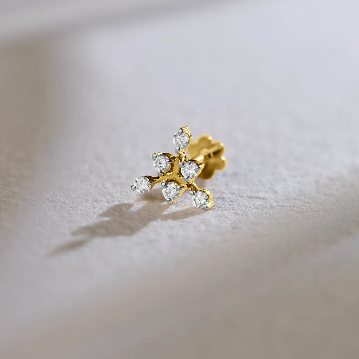 Product shot of an 18k gold stud with a multi-diamond flower-branch design
