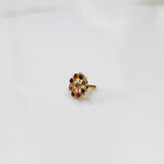 A gold cluster-design nose pin set with multiple oval multicolor stones in purple, red and pink, placed on a white background