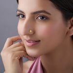 Close-up of woman wearing gold daisy-shaped nose pin