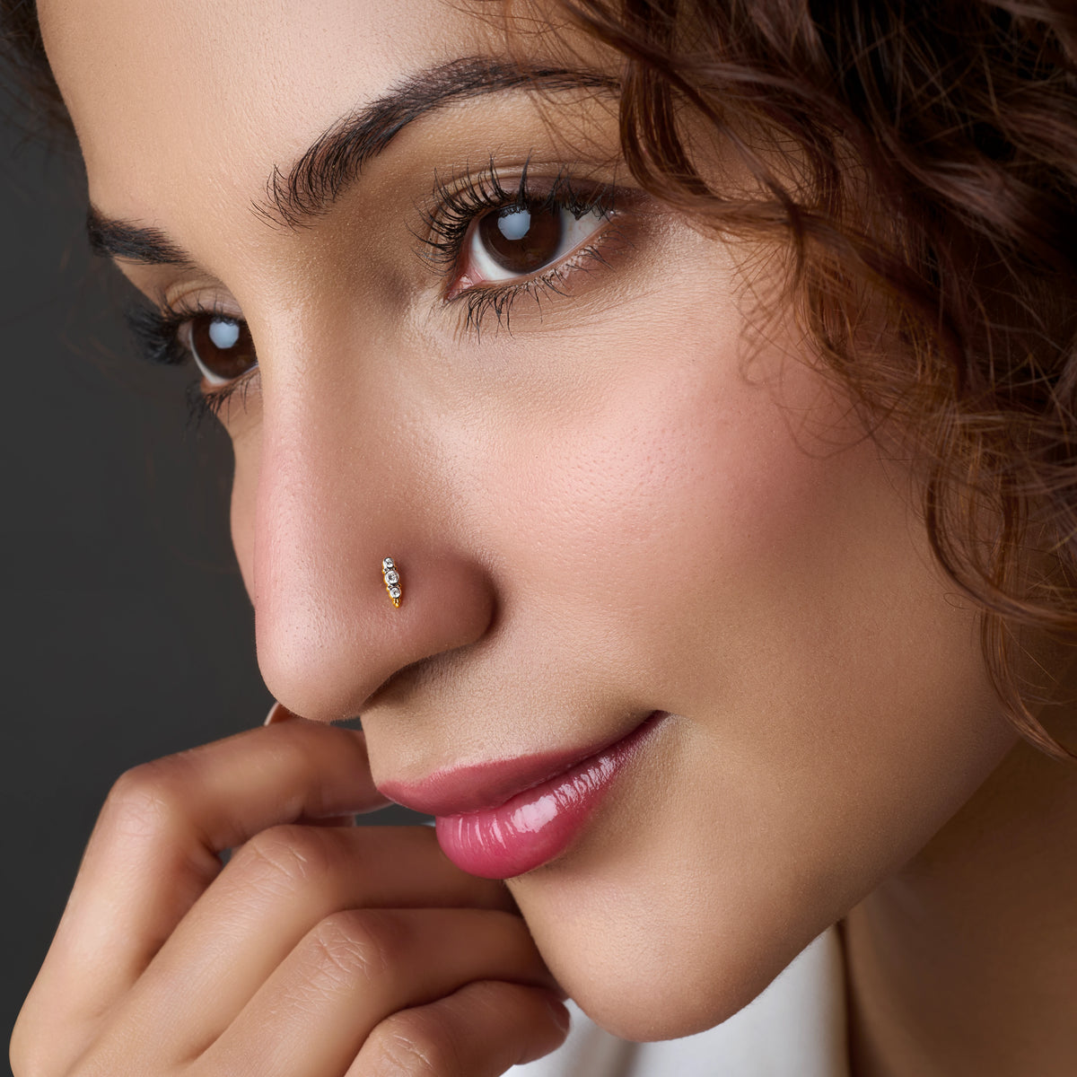 Model wearing thin gold nose ring with stones