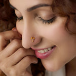 Woman wearing gold dangle nose pin with red and white stones