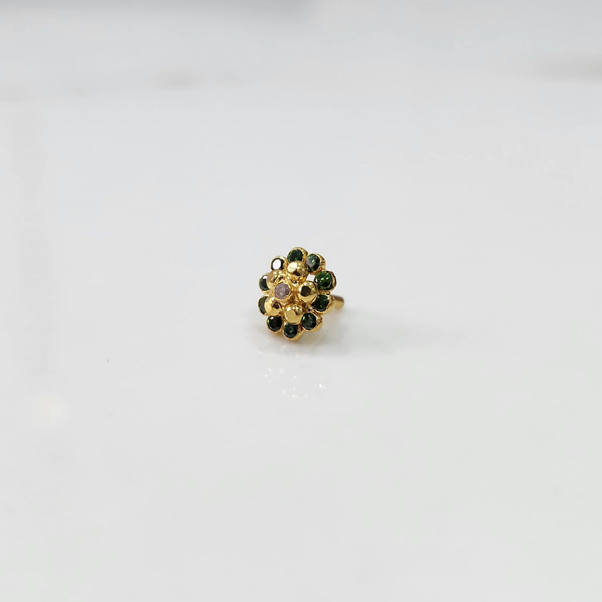 Gold floral ring with emerald-green outer stones and gold inner stones