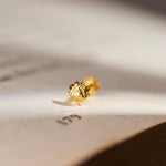 Gold faceted cluster stud earring, close-up on paper