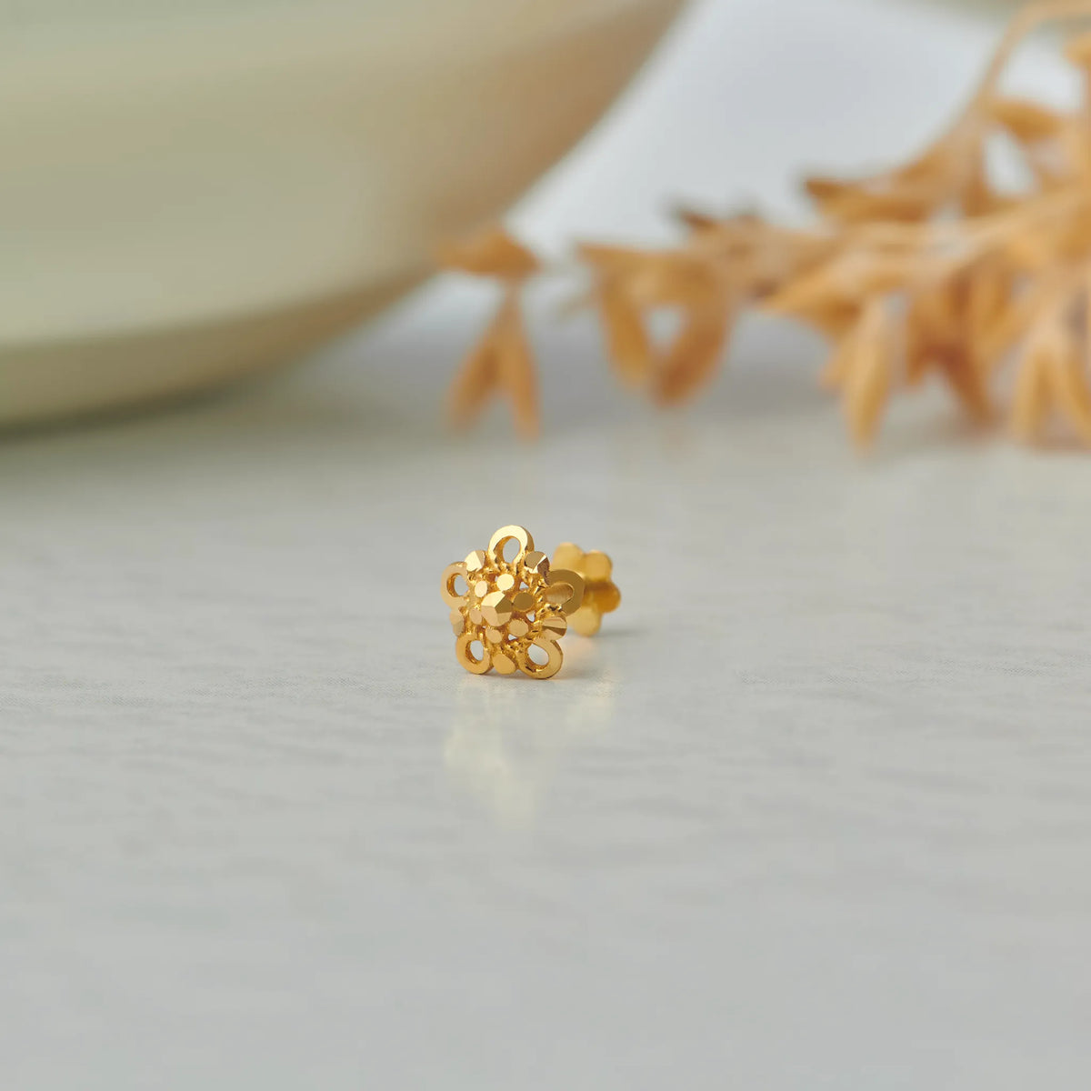 Gold flower-shaped stud earring with filigree cutout design
