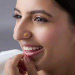 Close-up of a smiling woman wearing a small gold star flower nose pin