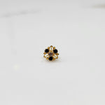 Close-up of gold ring featuring black stones and clear center in filigree setting