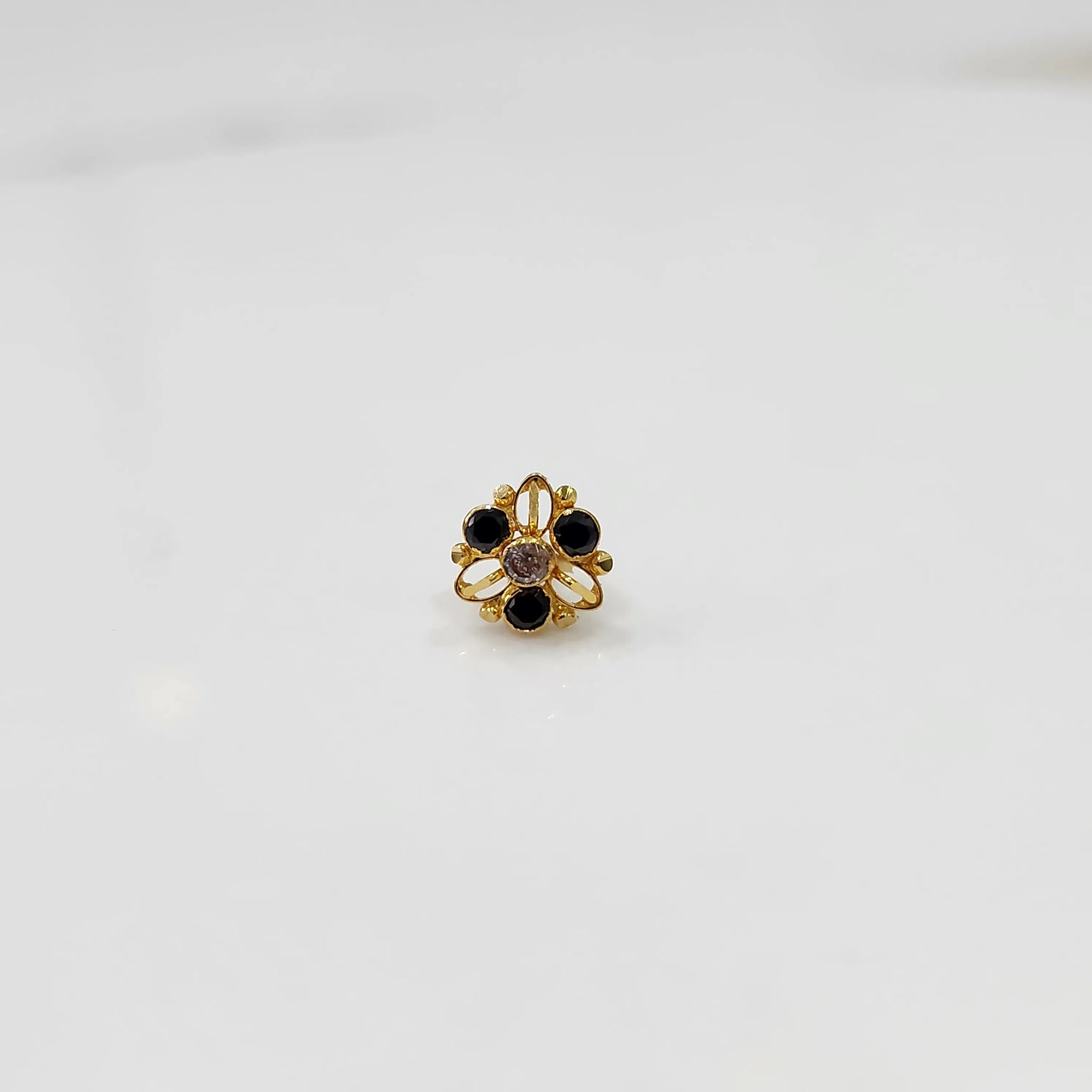 Close-up of gold ring featuring black stones and clear center in filigree setting