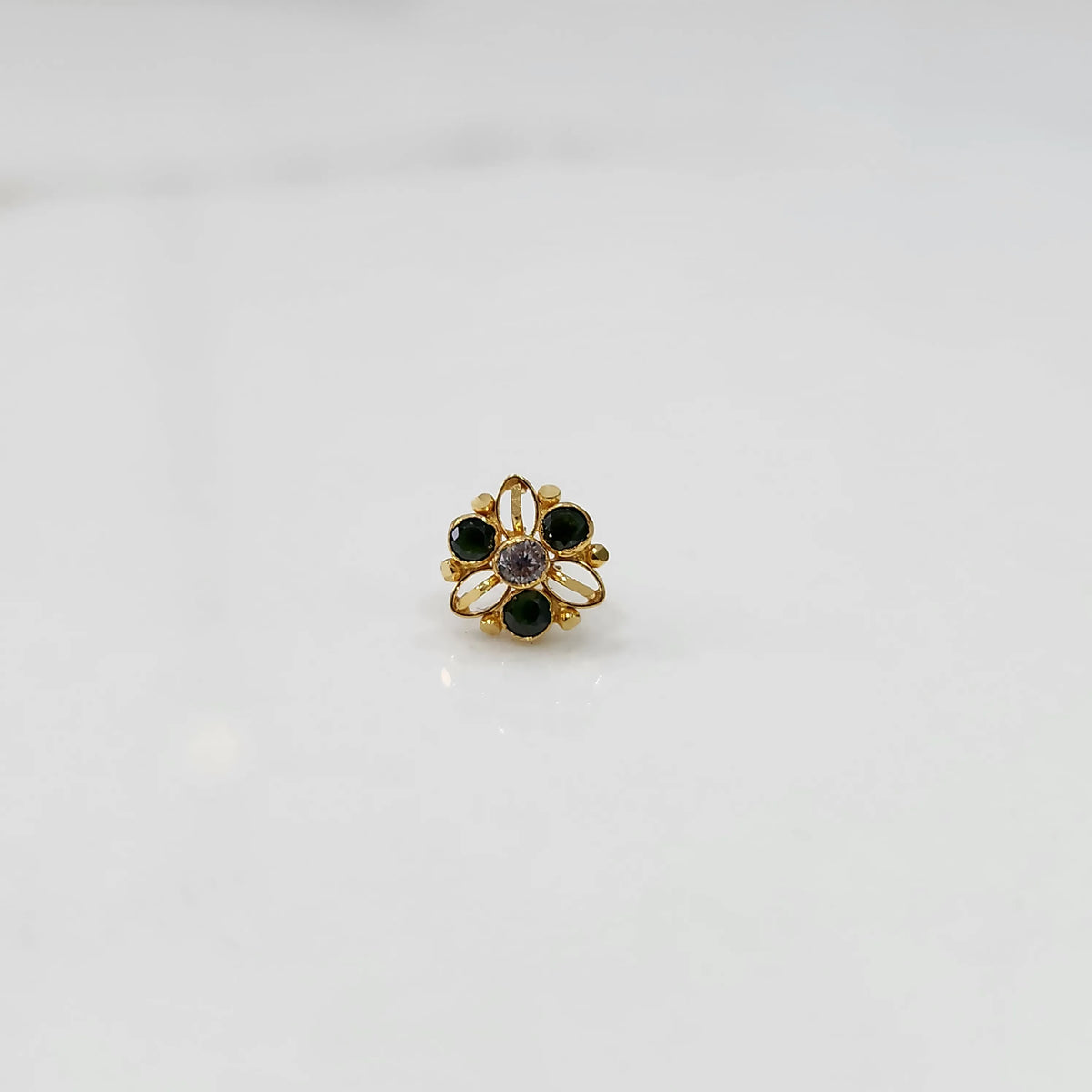 Top view of gold filigree ring with green oval gemstones