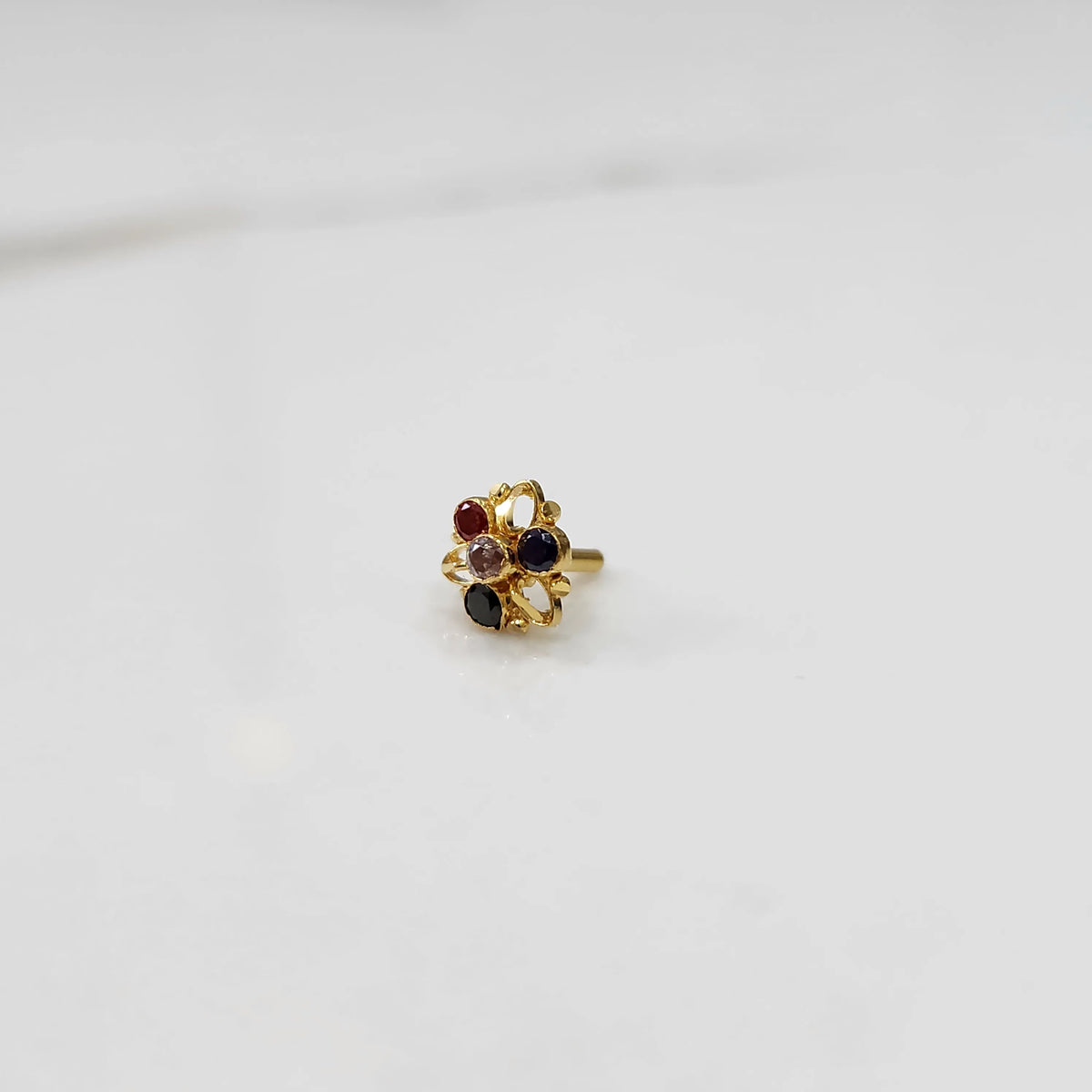 Traditional gold ring featuring an open petal design with red, blue and black stones