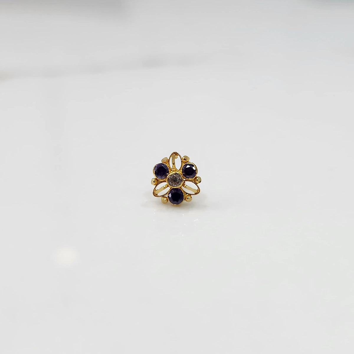 Top view of gold filigree ring with purple round gemstones