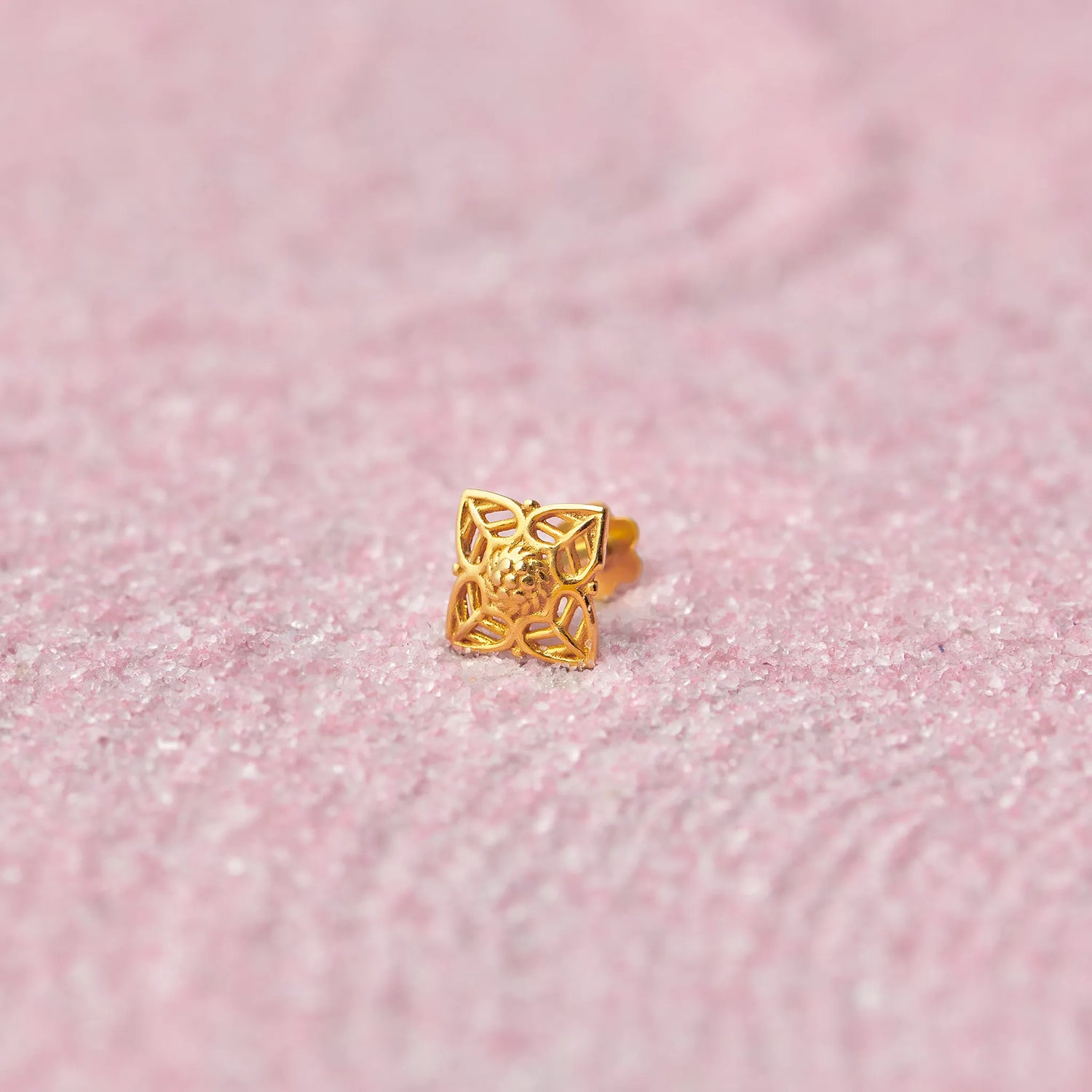 Gold floral cutwork nose stud in diamond shape on pink glitter background