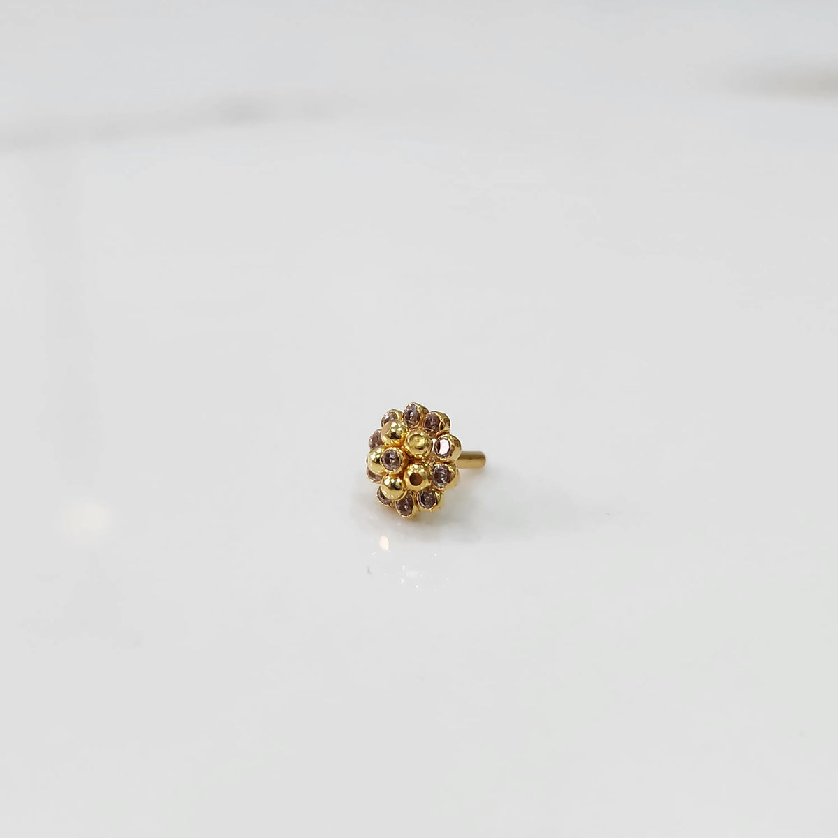 Side view of gold floral nose pin with lavender and clear stones