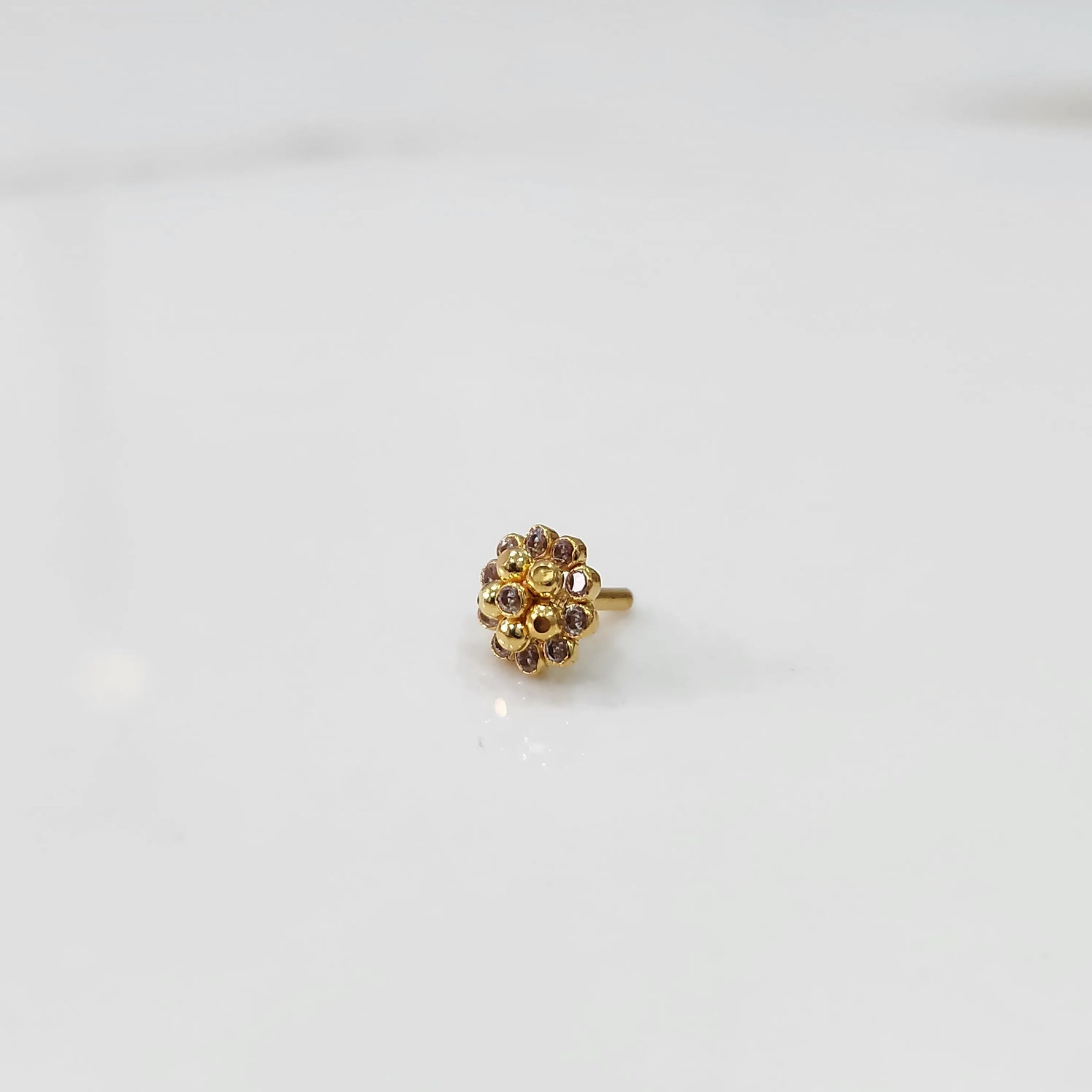 Side view of gold floral nose pin with lavender and clear stones