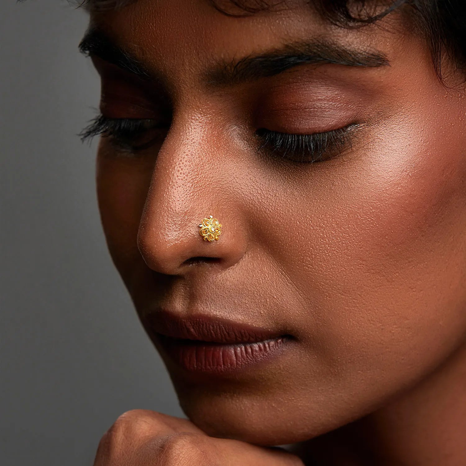 Gold floral nose stud worn on nostril, close-up lifestyle shot