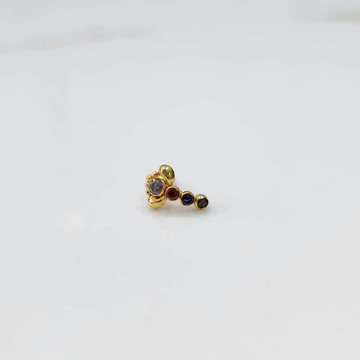Front view of gold nose pin with multicolor floral head and stone trail