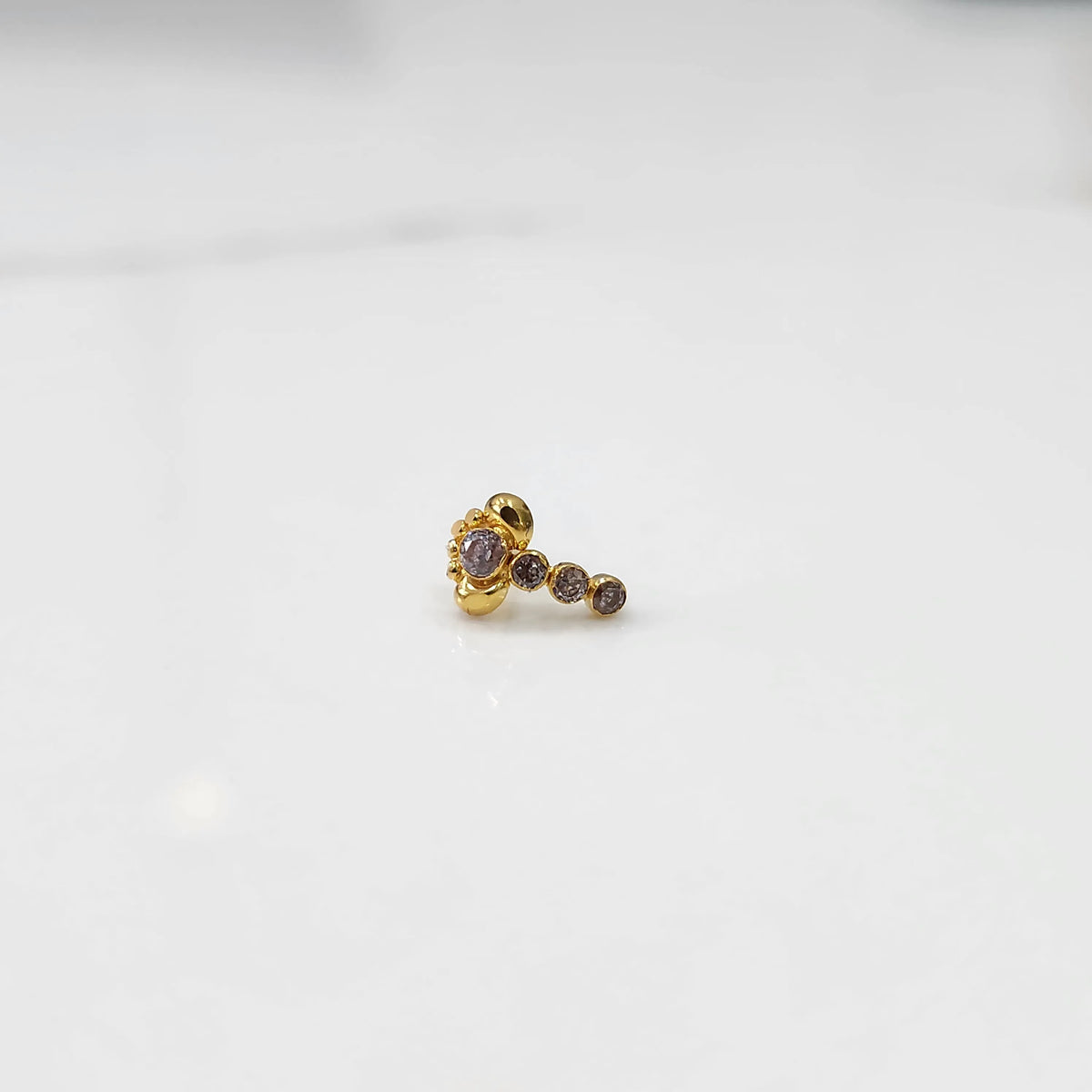 Front view of gold nose pin with pink floral head and stone trail