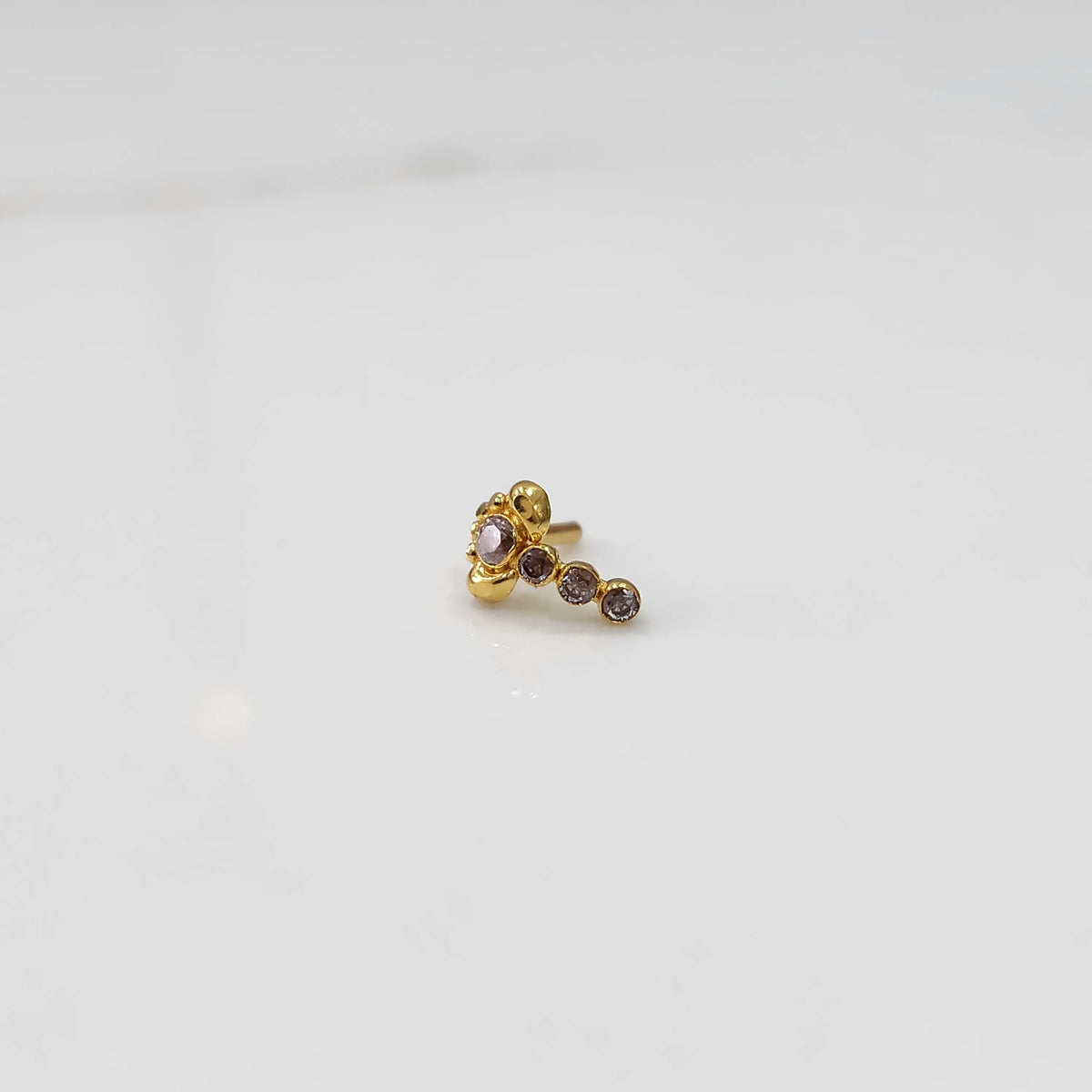 Gold nose pin with pink floral head and graduated stone trail 