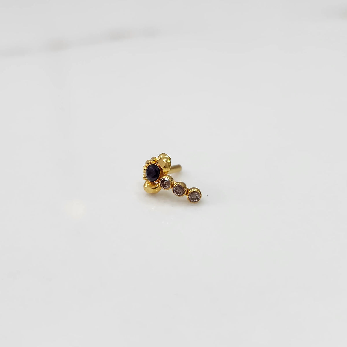 Gold nose pin with purple floral head and linear stone trail