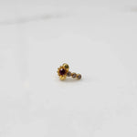 Front view of gold nose pin with red floral head and stone trail