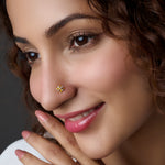Woman wearing a floral gold nose pin with diamond accents