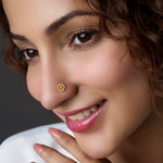 Close-up of flower-shaped gold nose stud with center stone