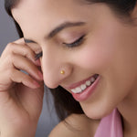 Close-up of a smiling woman wearing a small gold flower nose pin