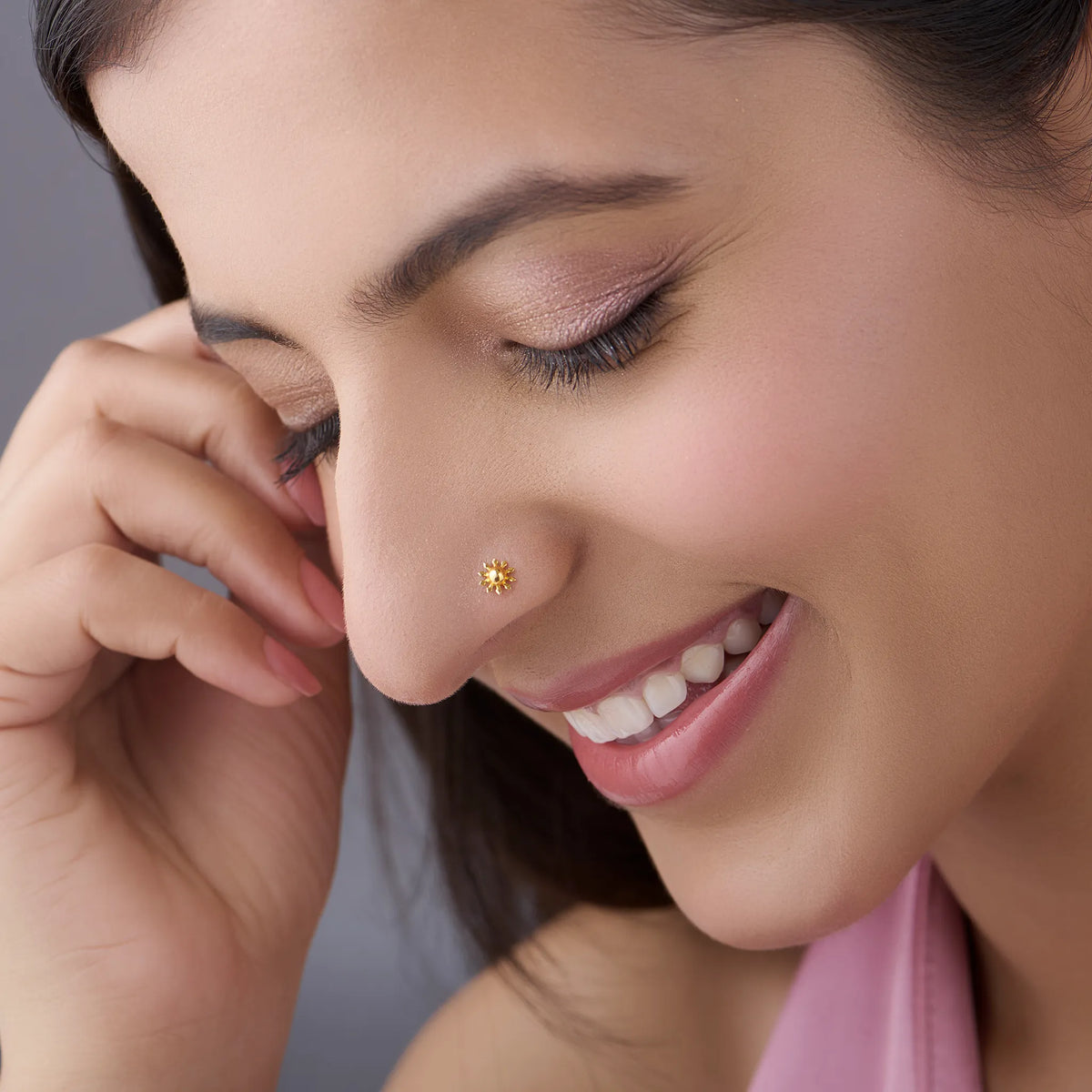 Close-up of a smiling woman wearing a small gold flower nose pin