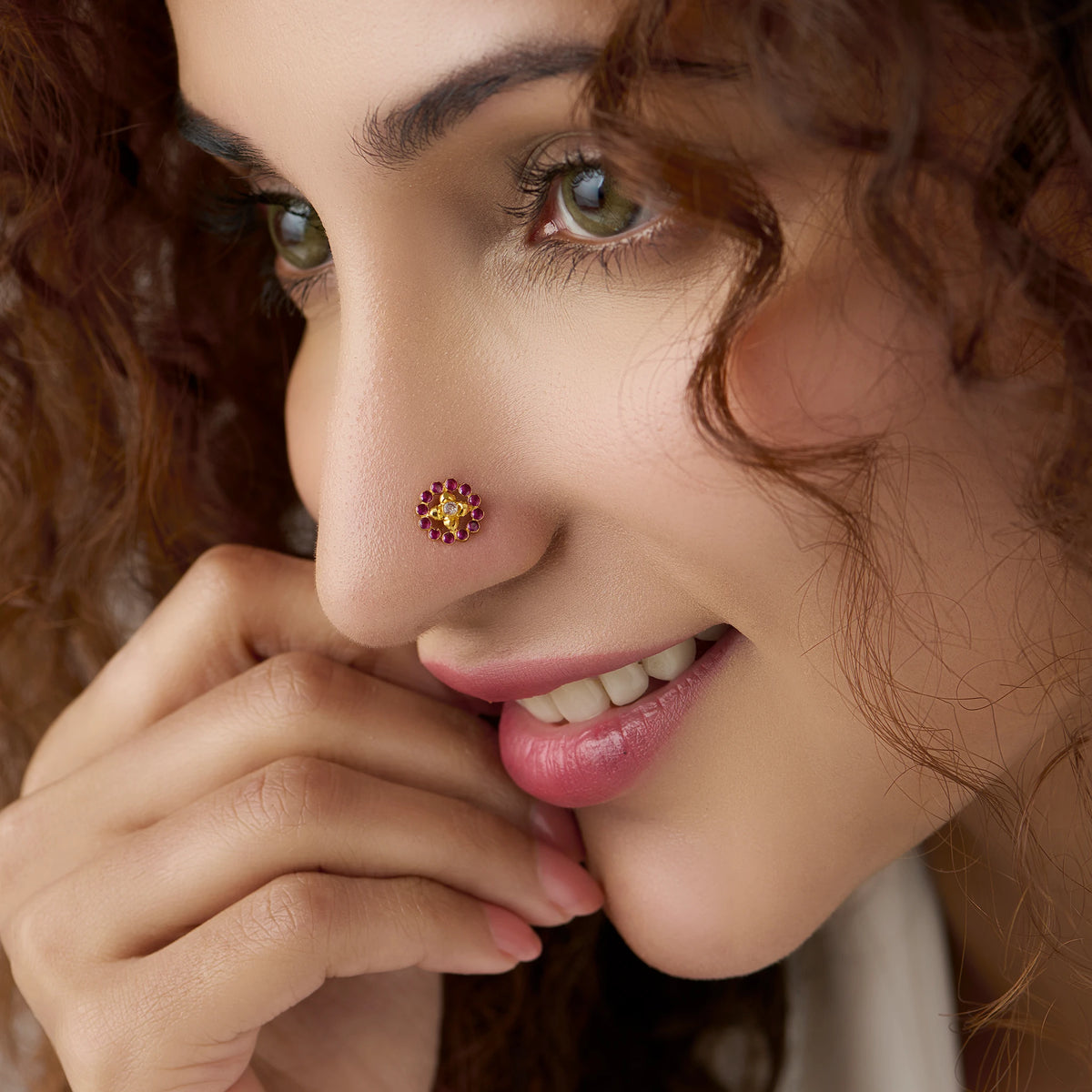 Woman wearing gold flower nose pin with pink and yellow stones