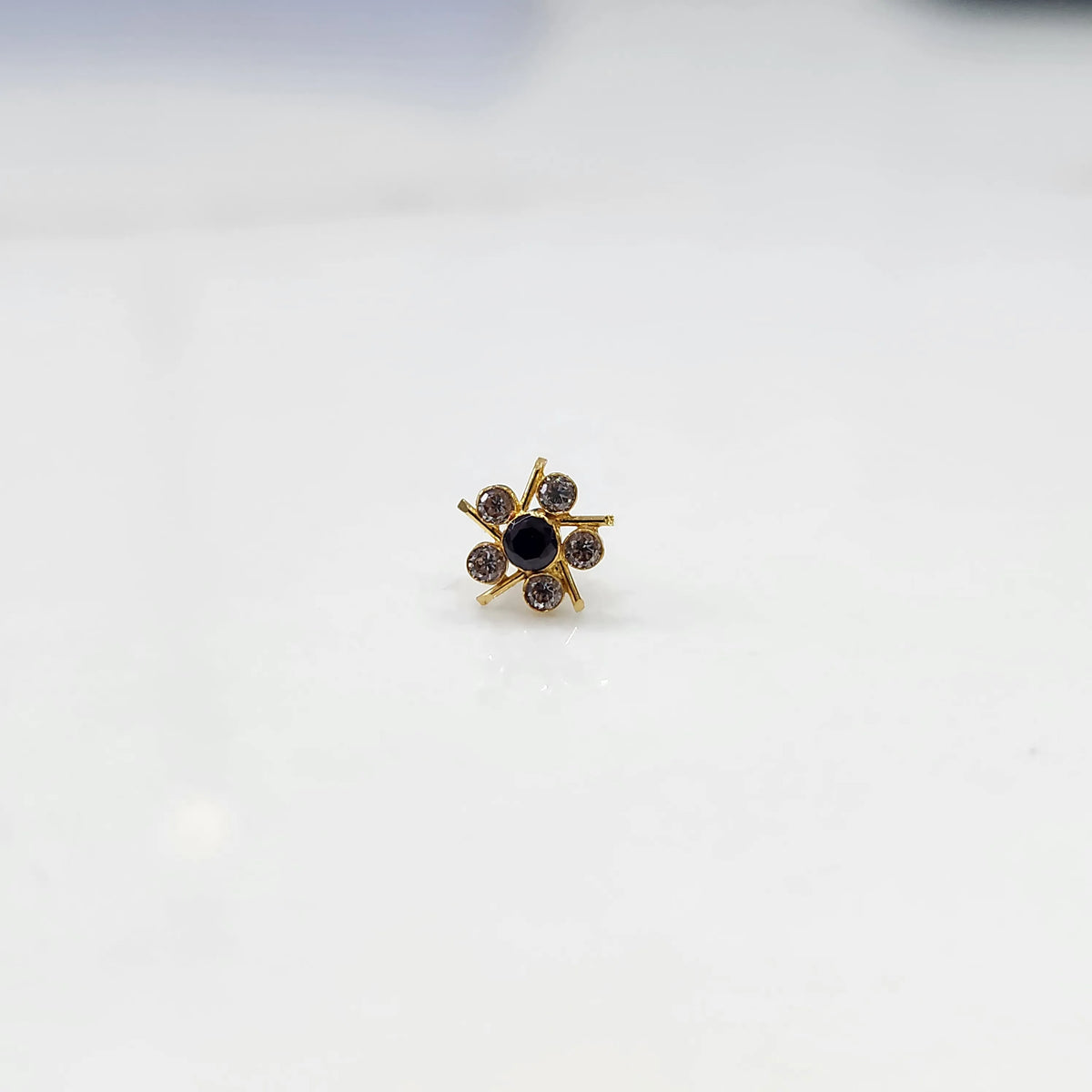 Top view of gold ring with black center stone and prong-set petals