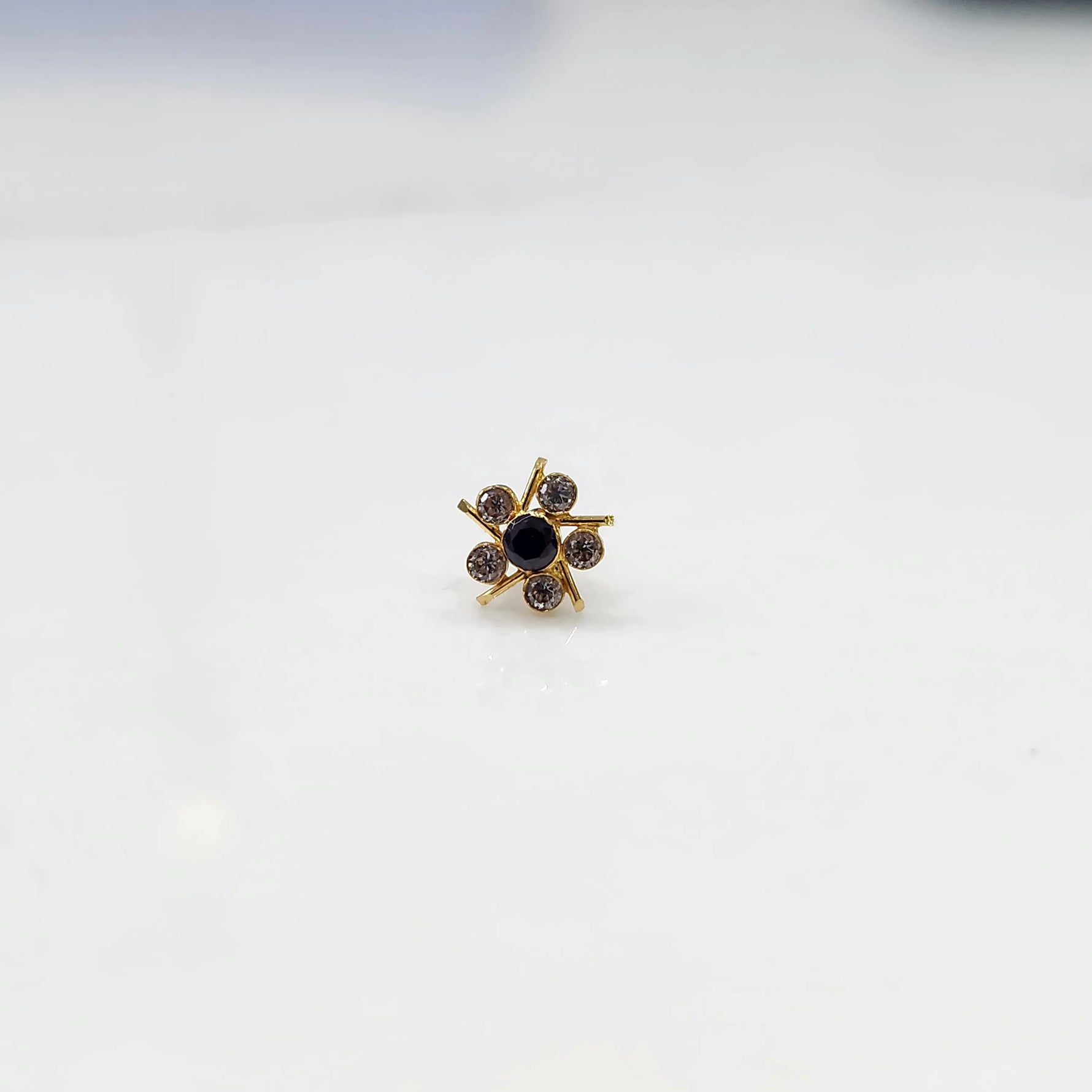 Top view of gold ring with black center stone and prong-set petals