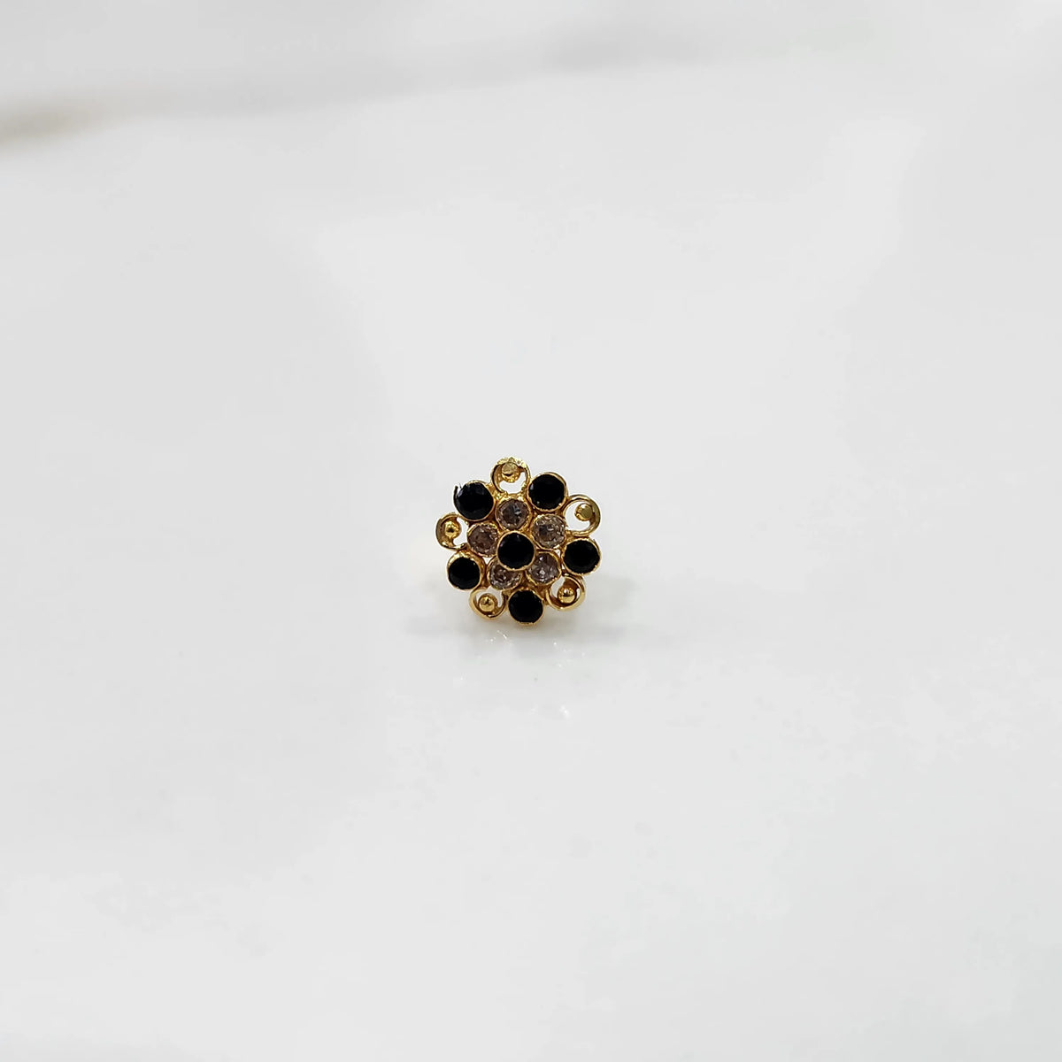 Gold flower ring with black and clear gemstones in halo setting