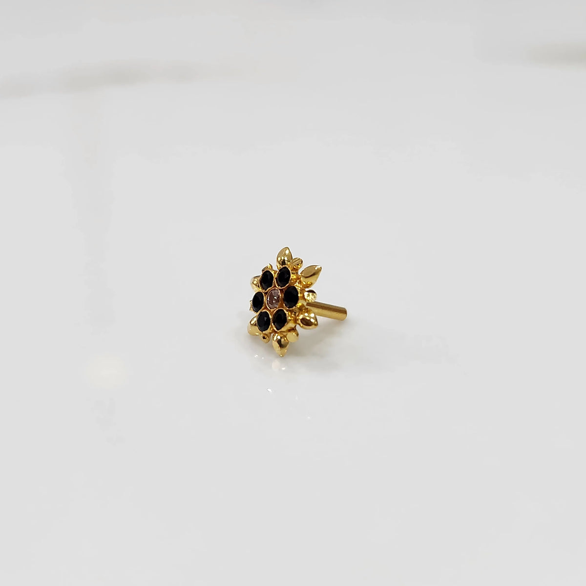 Side view of gold flower ring with black and clear gemstones