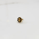 Top view of gold flower ring with black gemstones and clear center stone