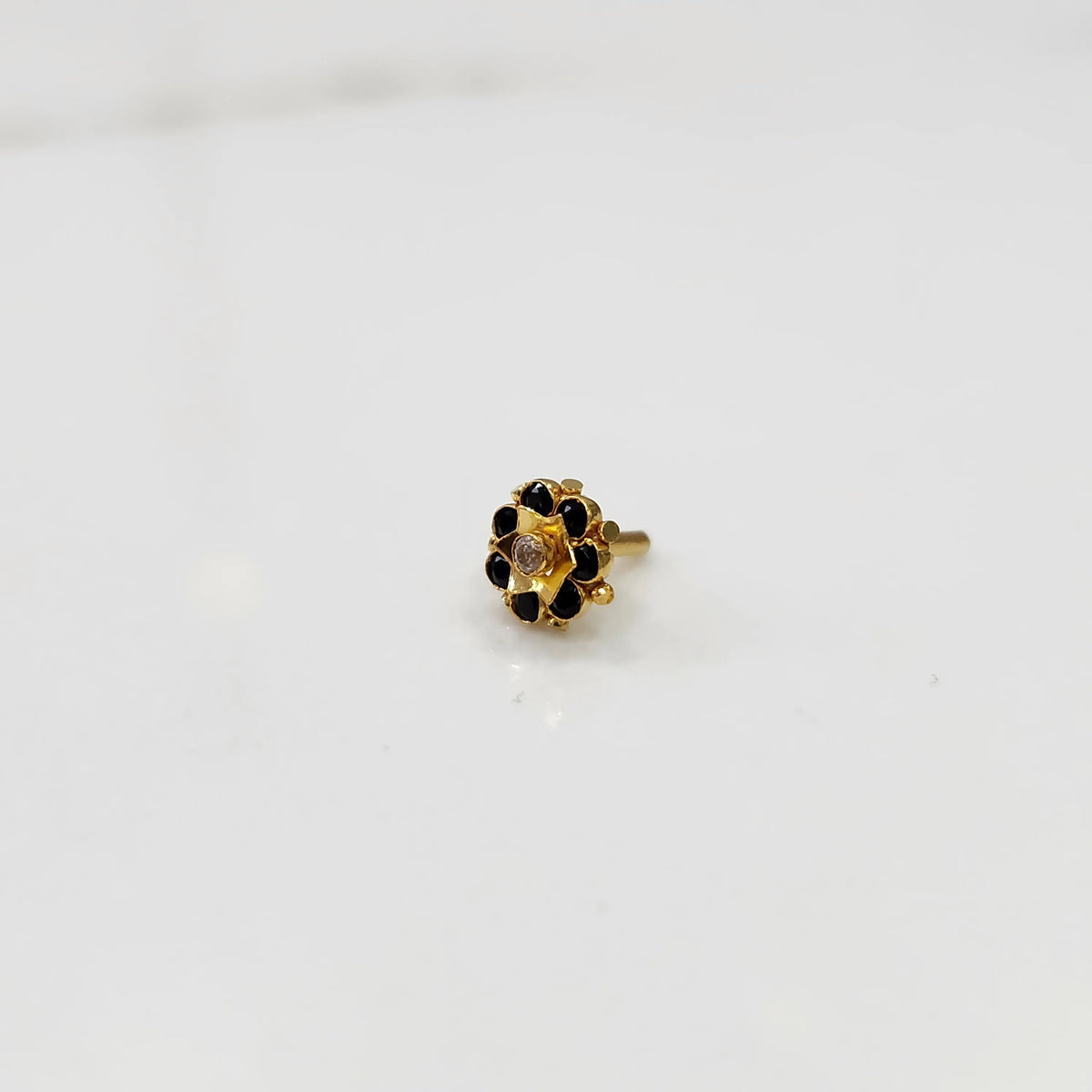 Top view of gold flower ring with black gemstones and clear center stone