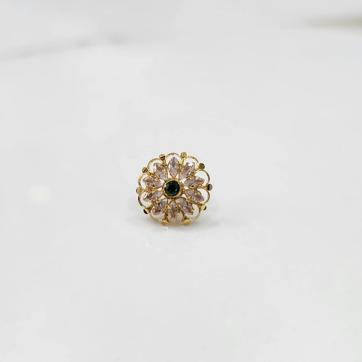 Gold flower ring with clear and green gemstones, front view