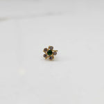 Close-up of gold ring featuring green center with pink round gemstones
