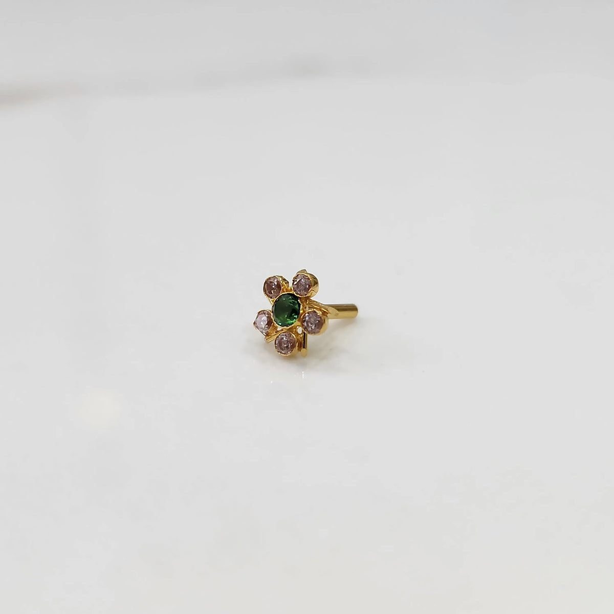 Gold ring with emerald-cut green center stone and pink round stones