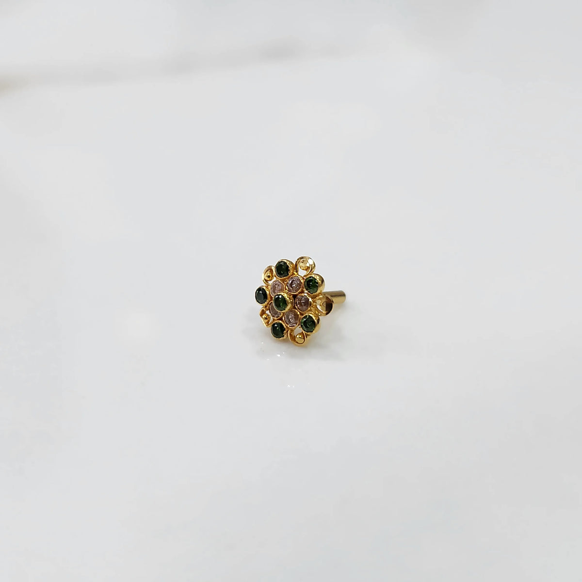 Gold flower ring with green and clear gemstones in halo setting