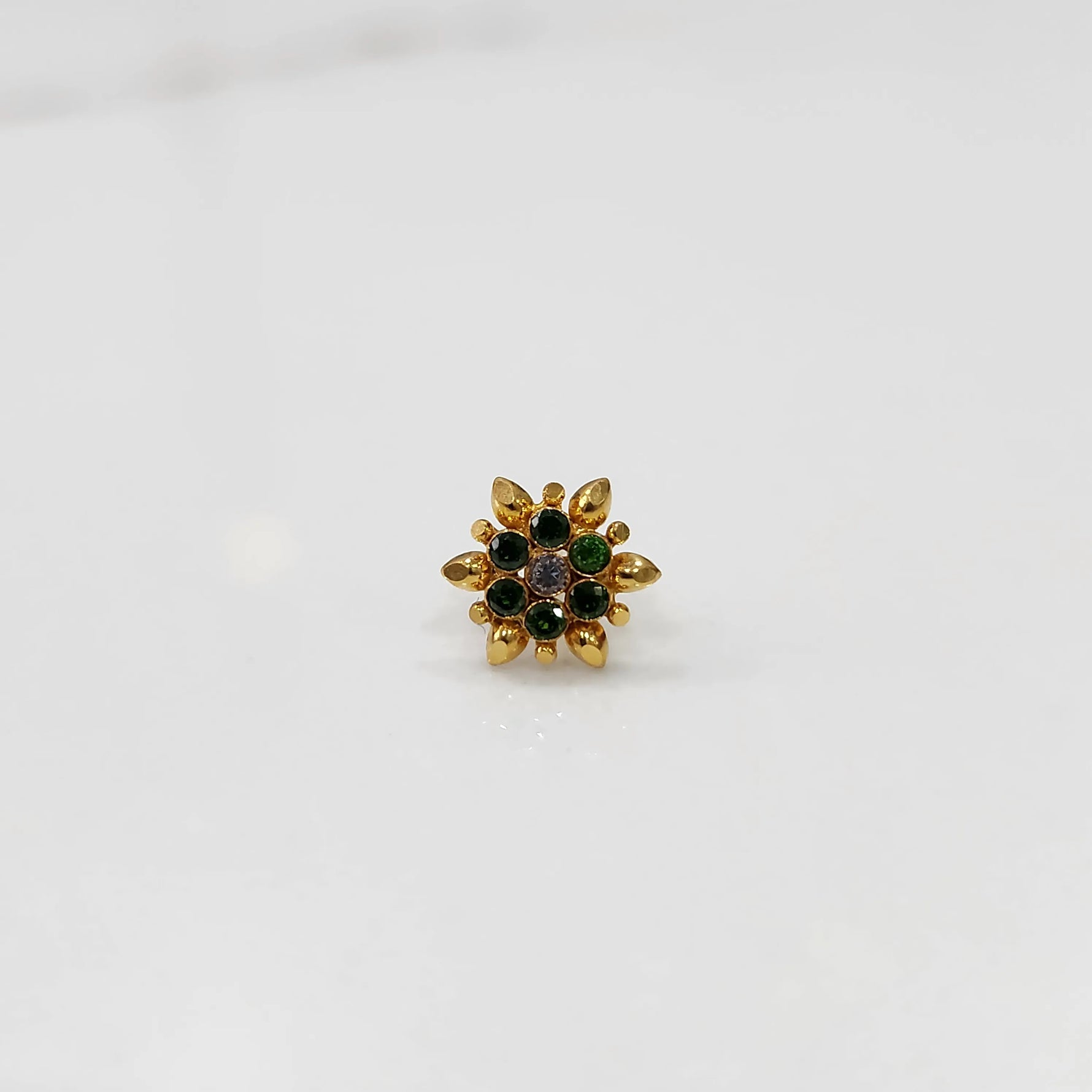 Gold flower ring with green and clear gemstones, front view