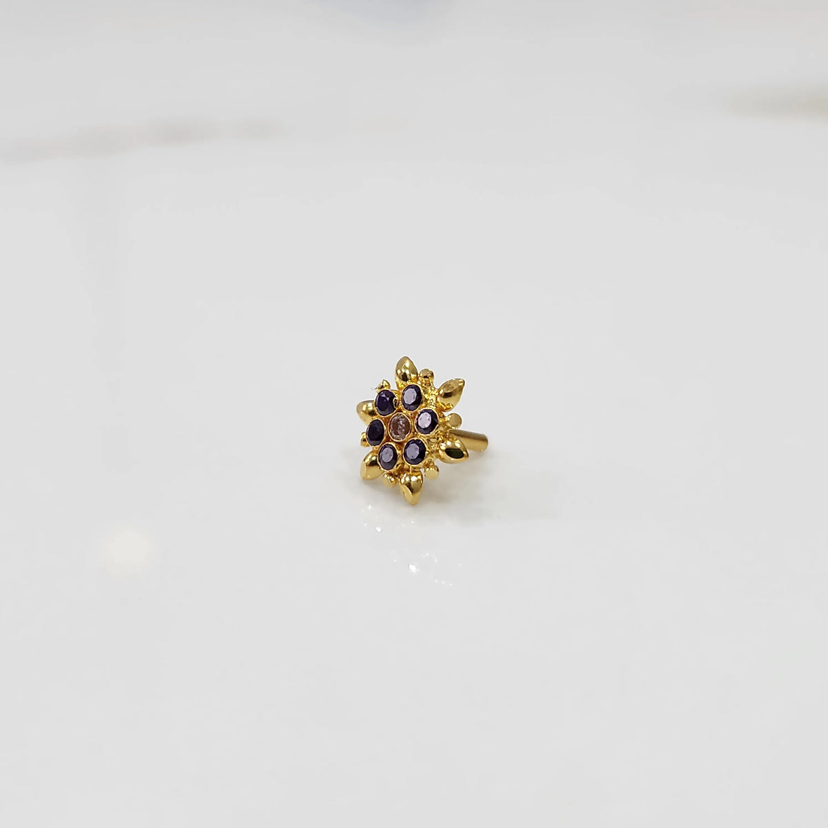 Gold flower ring with purple and black gemstones, front view
