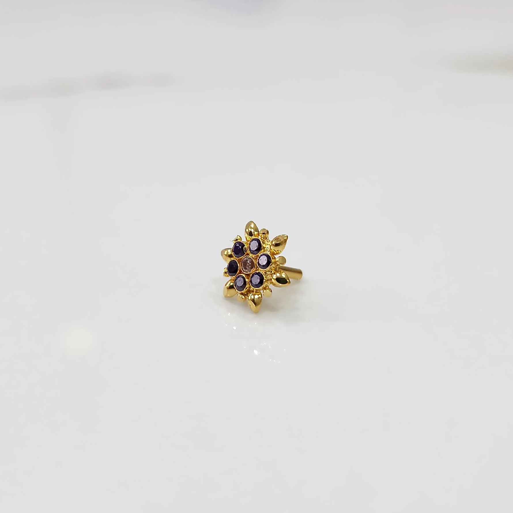 Gold flower ring with purple and black gemstones, front view