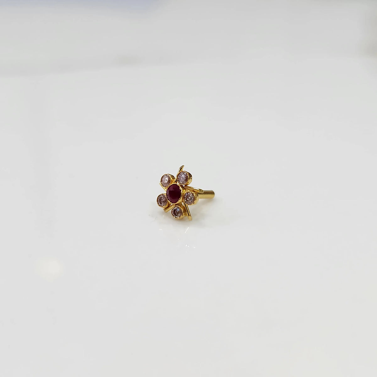 Gold ring with ruby-red center stone and pink round petal stones