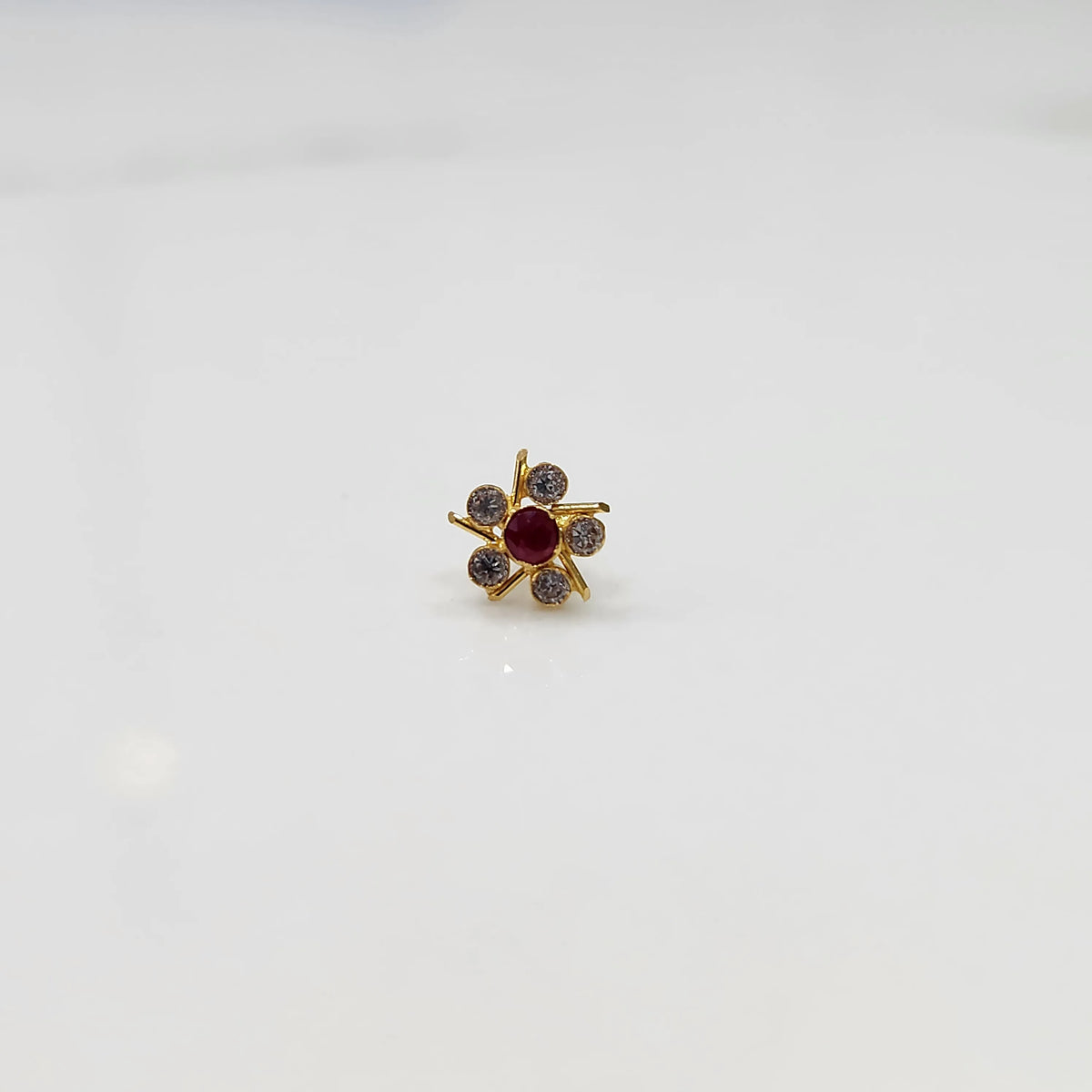 Top view of gold ring with ruby-red center stone and prong-set petals