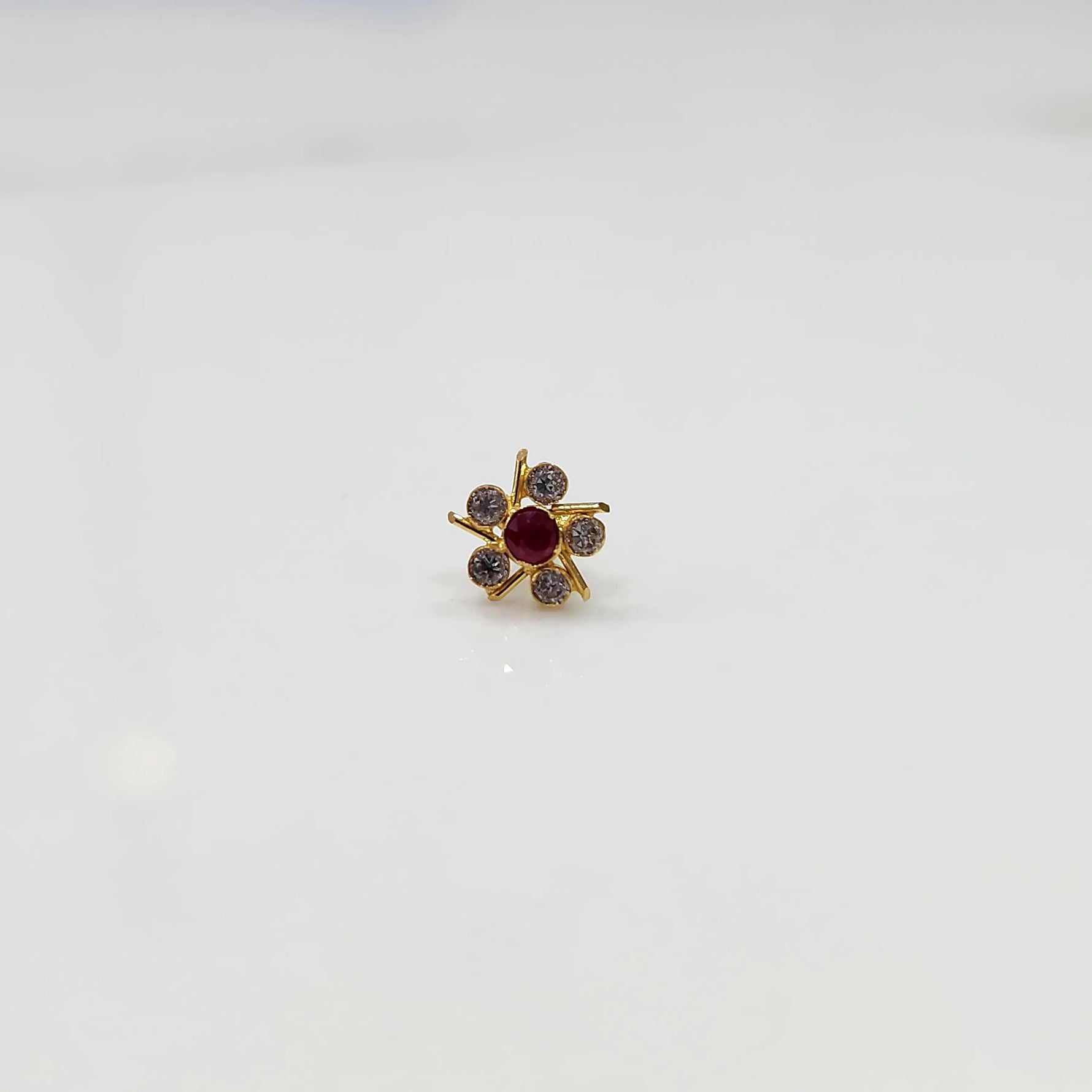 Top view of gold ring with ruby-red center stone and prong-set petals