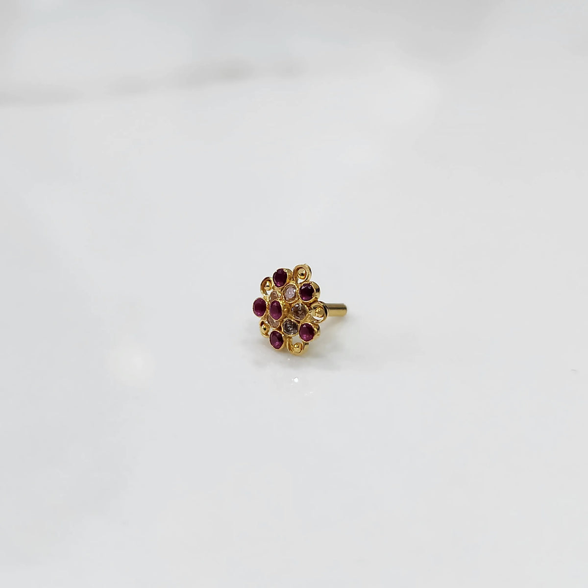 Gold flower ring with red and clear gemstones in halo setting