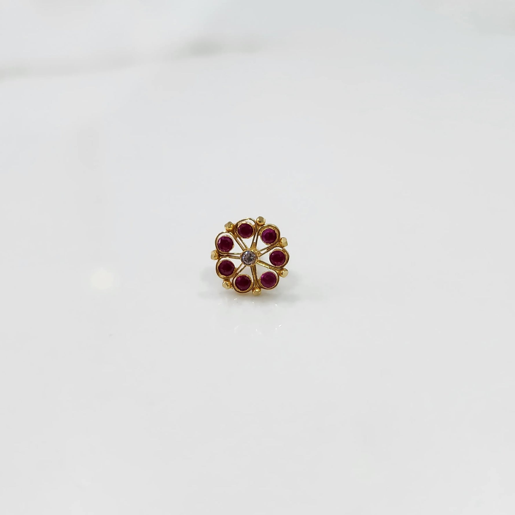 Front view of gold ring with red gemstone petals