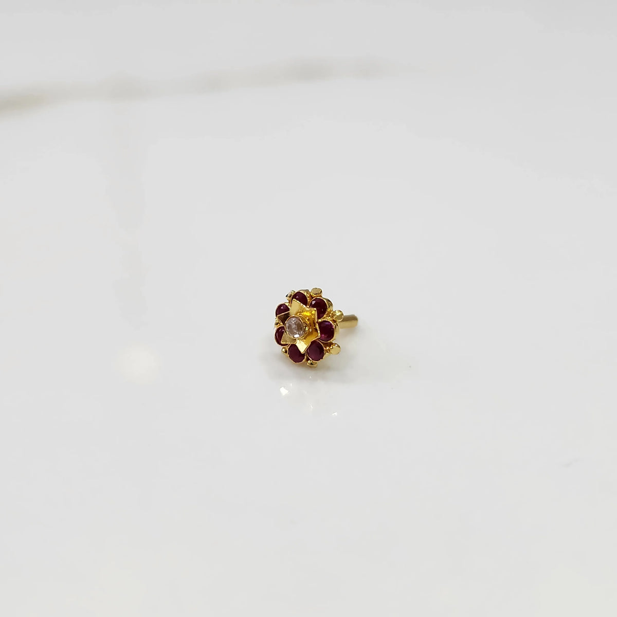 Gold flower ring with red gemstones and clear center stone