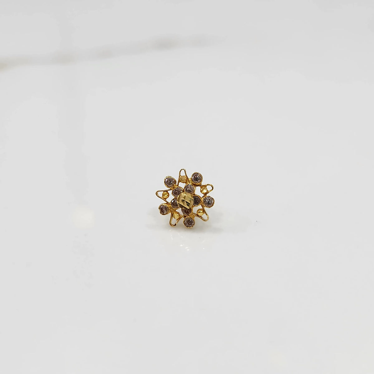 Top-down view of gold ring with square center stone and floral gold petals